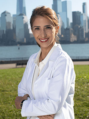Dr. Fara Vossughi standing outside in her white lab jacket smiling